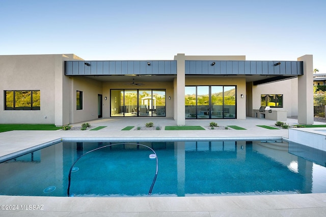 view of swimming pool featuring ceiling fan, an outdoor kitchen, and a patio area