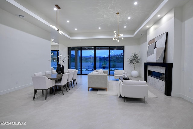 living room featuring a tile fireplace, a chandelier, and a tray ceiling