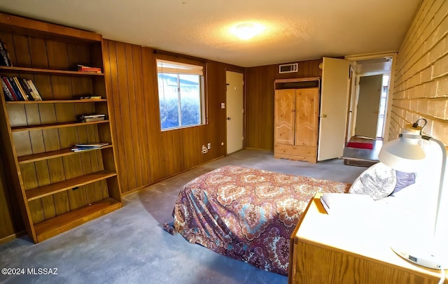 carpeted bedroom with wood walls and a textured ceiling