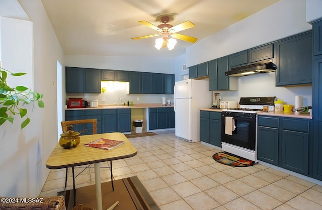 kitchen featuring blue cabinetry, white fridge, range with gas cooktop, vaulted ceiling, and light tile patterned flooring