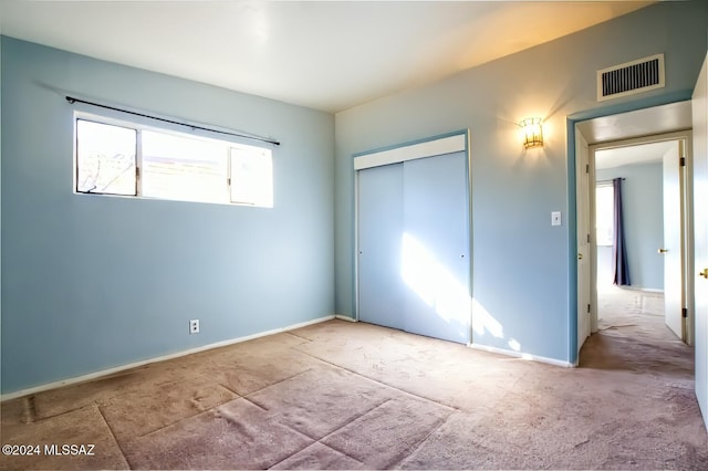 unfurnished bedroom featuring light carpet and a closet