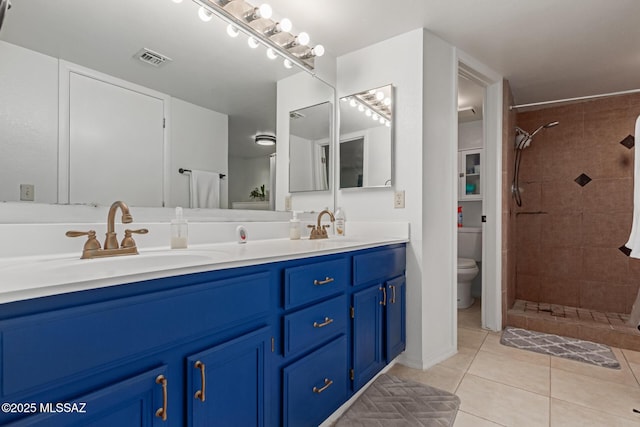 bathroom featuring tiled shower, toilet, tile patterned flooring, and vanity