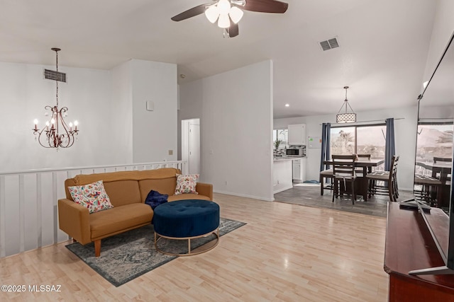 living room featuring ceiling fan with notable chandelier and light hardwood / wood-style floors