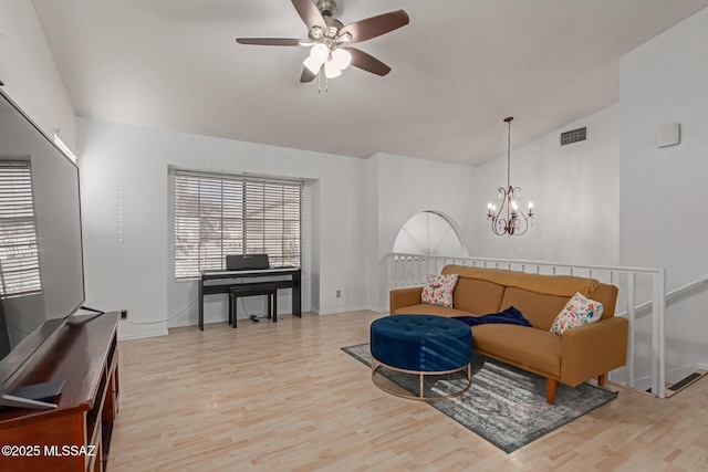 sitting room with light wood-type flooring, vaulted ceiling, and ceiling fan with notable chandelier