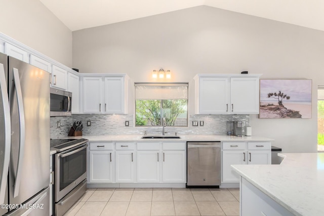 kitchen featuring appliances with stainless steel finishes, sink, light tile patterned floors, and white cabinets