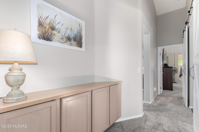 hallway with a barn door and light carpet