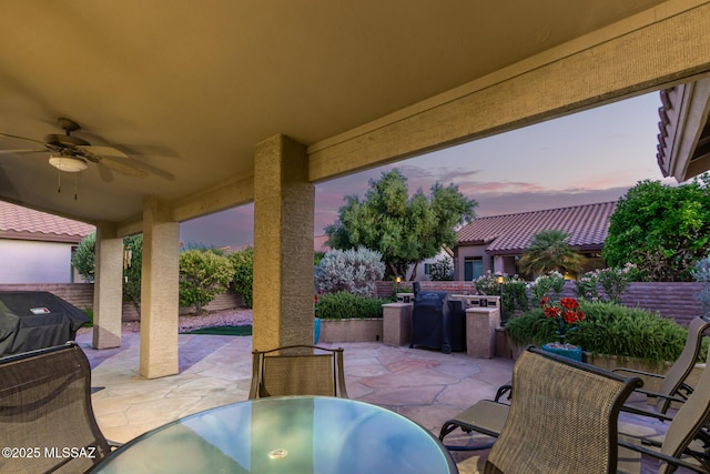 patio terrace at dusk featuring ceiling fan