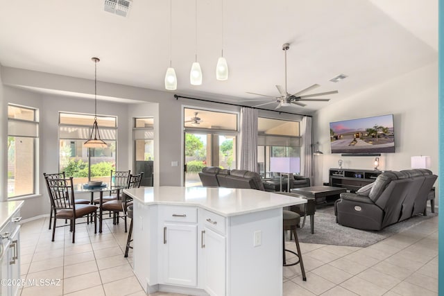 kitchen with a breakfast bar, a center island, white cabinets, light tile patterned flooring, and decorative light fixtures