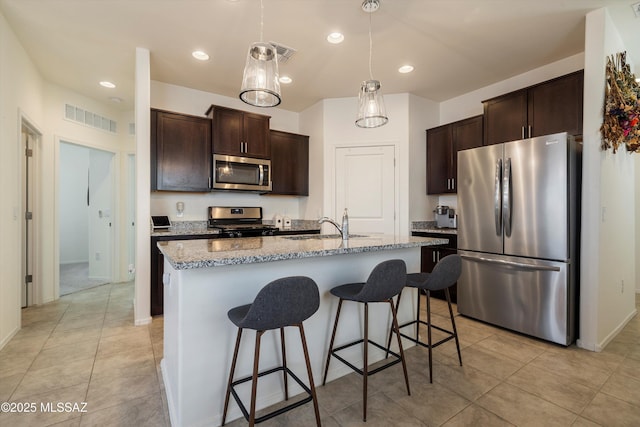 kitchen with stainless steel appliances, sink, a center island with sink, and dark brown cabinetry