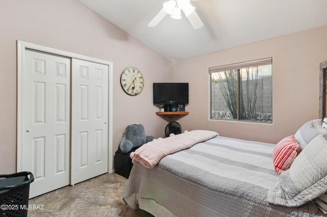 bedroom featuring a closet, a ceiling fan, stone finish flooring, and lofted ceiling