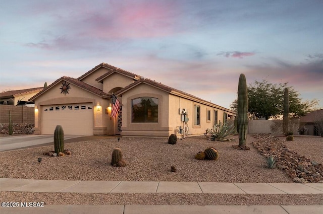 ranch-style home with concrete driveway, an attached garage, fence, and stucco siding