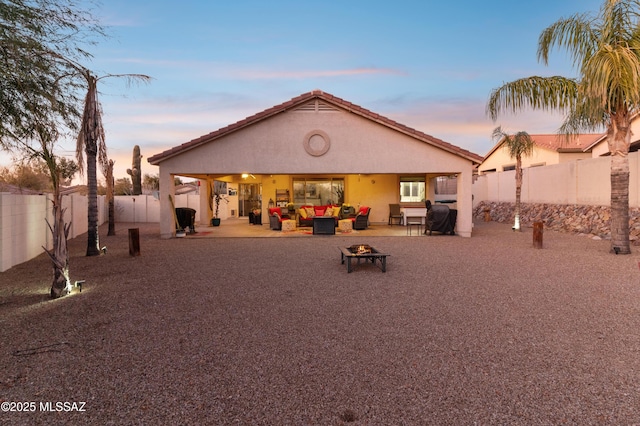 rear view of property featuring a fenced backyard, an outdoor living space with a fire pit, a patio area, and stucco siding