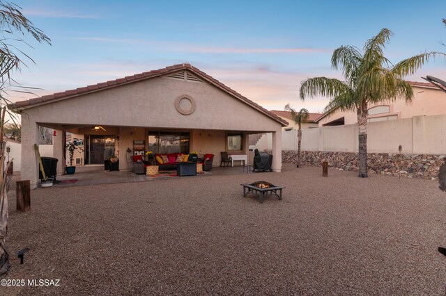 rear view of house featuring an outdoor living space with a fire pit, a fenced backyard, stucco siding, a patio area, and a tile roof