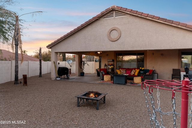 back of property at dusk featuring a fenced backyard, a patio, and stucco siding