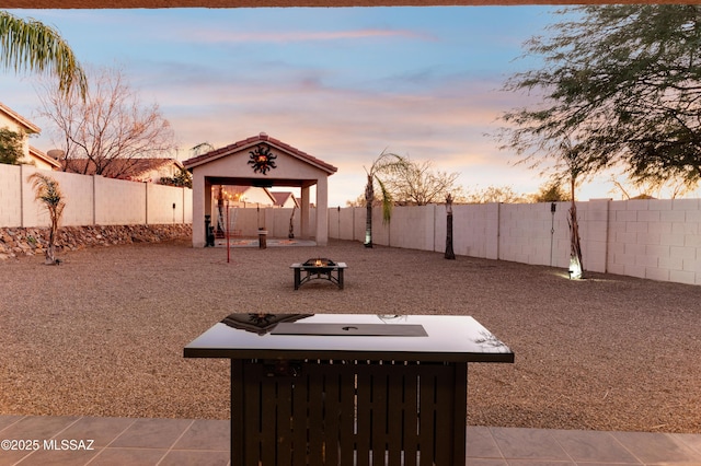 view of yard with a fenced backyard, a fire pit, and a gazebo