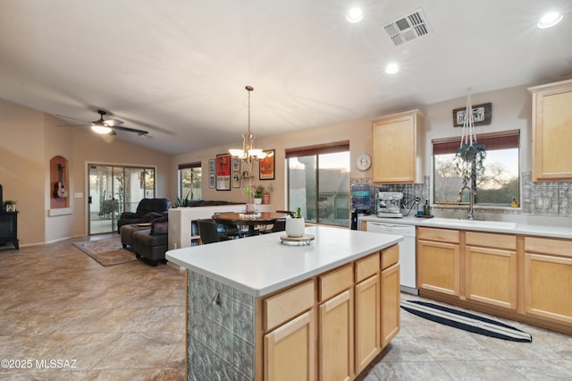 kitchen featuring visible vents, white dishwasher, vaulted ceiling, light brown cabinetry, and a sink