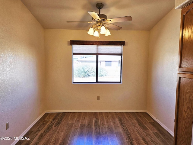 empty room with ceiling fan and dark hardwood / wood-style flooring