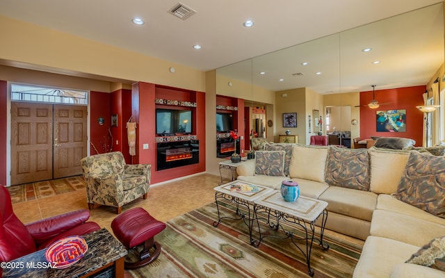 living area featuring recessed lighting, tile patterned flooring, visible vents, and a glass covered fireplace