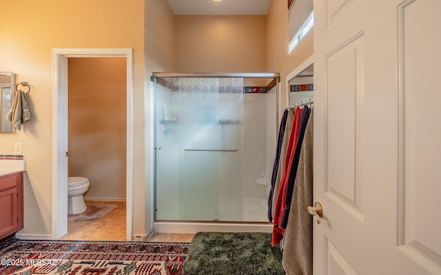 bathroom with toilet, vanity, a shower stall, and baseboards