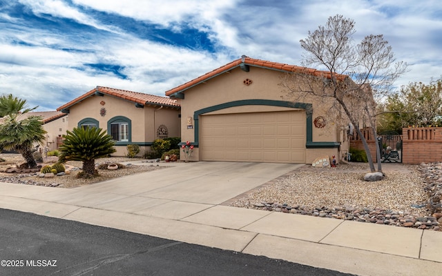 mediterranean / spanish house featuring driveway, a tile roof, an attached garage, fence, and stucco siding