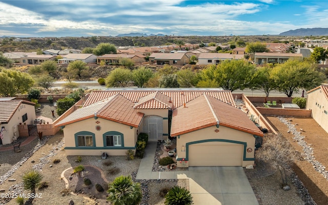 view of front of house featuring a residential view, a tiled roof, a mountain view, an attached garage, and stucco siding