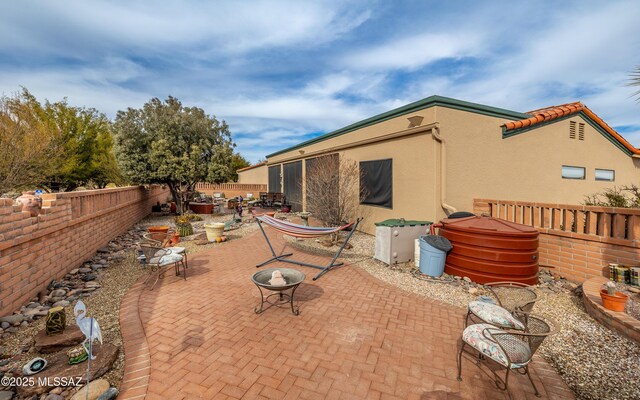 rear view of property featuring stucco siding, a patio area, an outdoor fire pit, and a fenced backyard