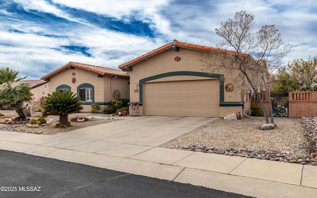 mediterranean / spanish-style house featuring stucco siding, fence, a tile roof, driveway, and an attached garage