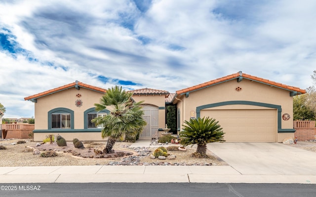 mediterranean / spanish-style home featuring a garage, fence, stucco siding, and concrete driveway