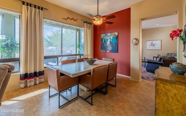 tiled dining space featuring baseboards and a ceiling fan