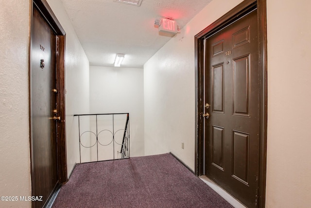 corridor featuring a textured ceiling and carpet