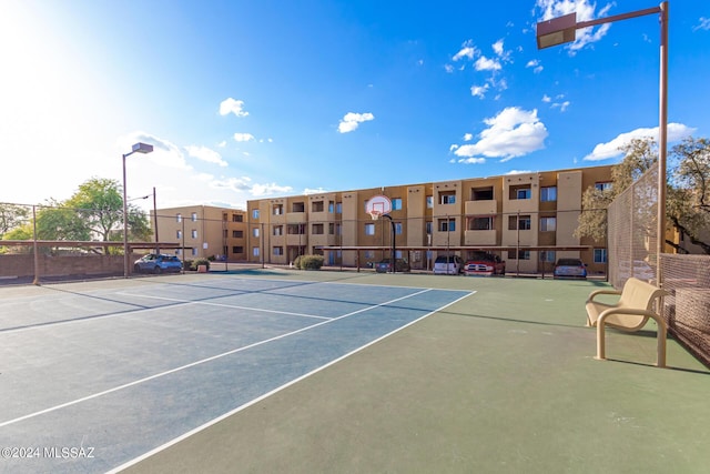 view of tennis court featuring community basketball court and fence