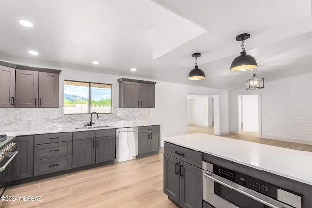 kitchen featuring sink, decorative light fixtures, light hardwood / wood-style flooring, appliances with stainless steel finishes, and backsplash