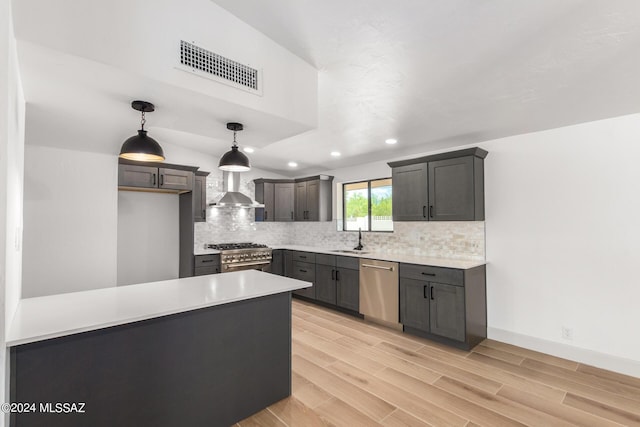 kitchen featuring sink, hanging light fixtures, light hardwood / wood-style floors, stainless steel appliances, and wall chimney range hood