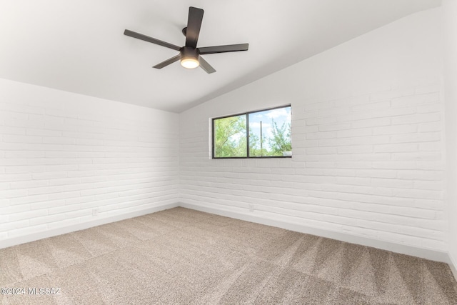 unfurnished room featuring ceiling fan, brick wall, lofted ceiling, and carpet