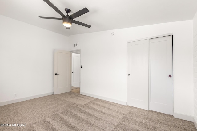 unfurnished bedroom featuring light colored carpet, ceiling fan, and a closet