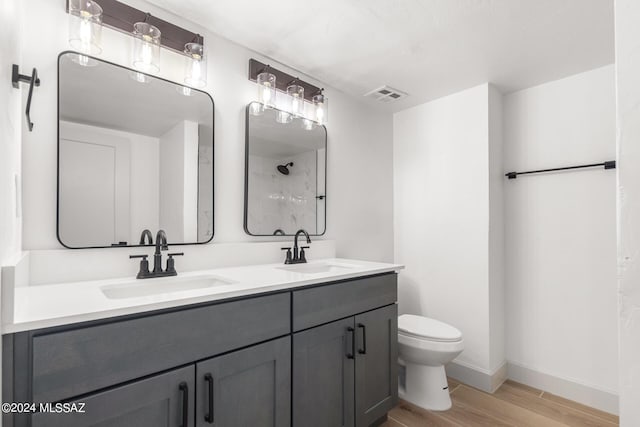 bathroom featuring hardwood / wood-style flooring, vanity, walk in shower, and toilet