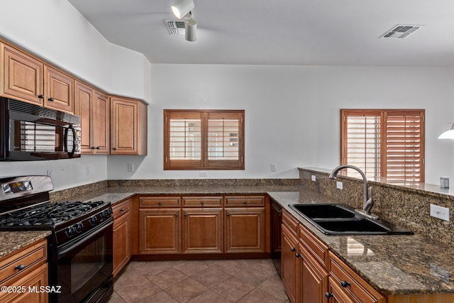 kitchen featuring sink, light tile patterned floors, kitchen peninsula, dark stone counters, and black appliances