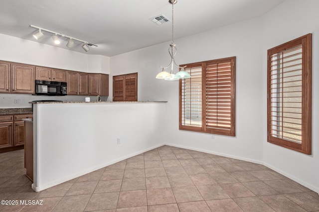 kitchen with pendant lighting, a notable chandelier, dark stone counters, and light tile patterned floors