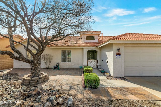 mediterranean / spanish home with a garage, a tiled roof, and stucco siding