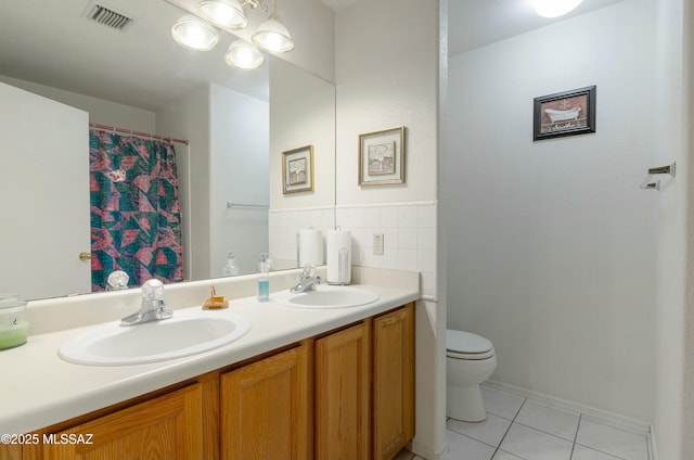 bathroom featuring visible vents, double vanity, a sink, and toilet