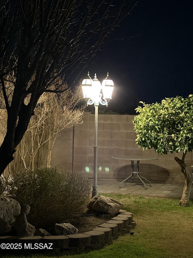 yard at night with a patio and fence