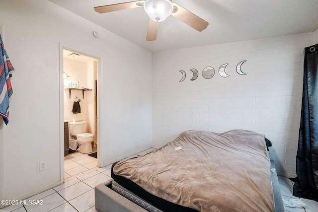 bedroom with ceiling fan, ensuite bathroom, brick wall, and light tile patterned floors