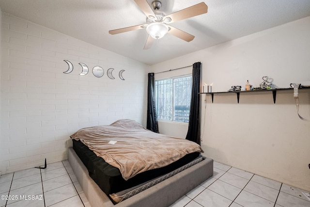 tiled bedroom featuring ceiling fan, brick wall, and lofted ceiling