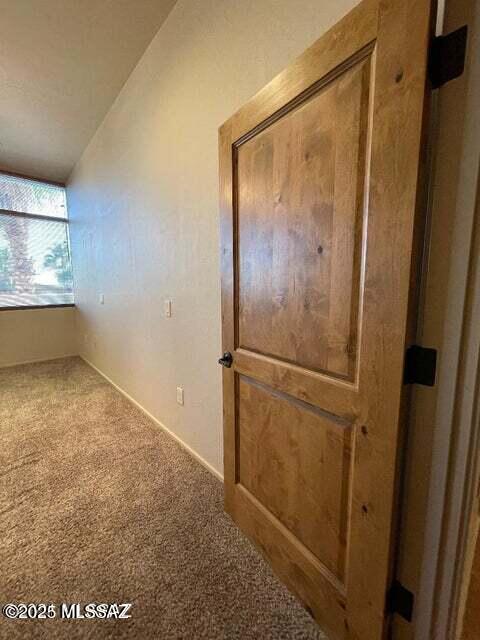 hall featuring lofted ceiling and carpet floors