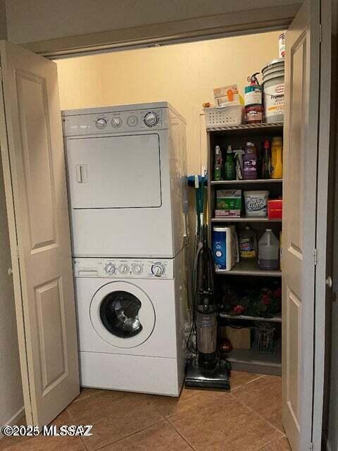 laundry area with tile patterned floors and stacked washing maching and dryer