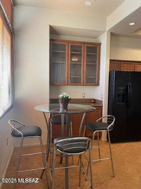 kitchen featuring light tile patterned floors and black refrigerator with ice dispenser