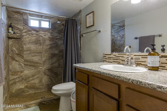 bathroom featuring vanity, toilet, a tile shower, and backsplash