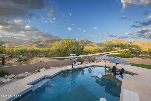 view of swimming pool featuring a patio area, a fenced in pool, and a mountain view