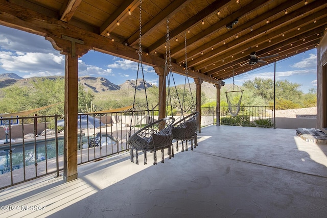 view of patio with a fenced in pool, a mountain view, and ceiling fan