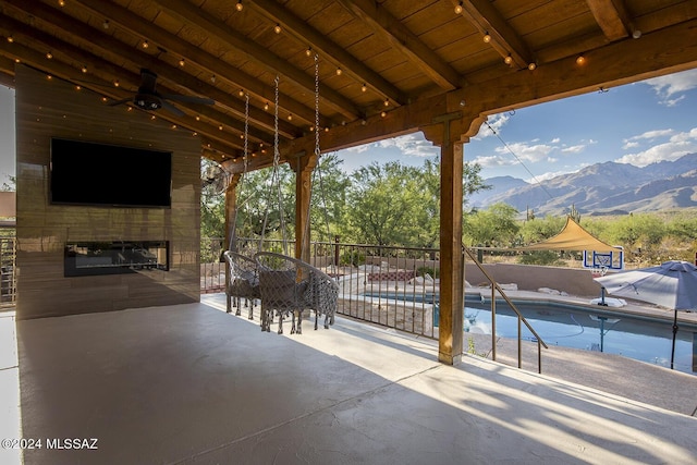 view of patio / terrace featuring a fenced in pool, a mountain view, a ceiling fan, and fence